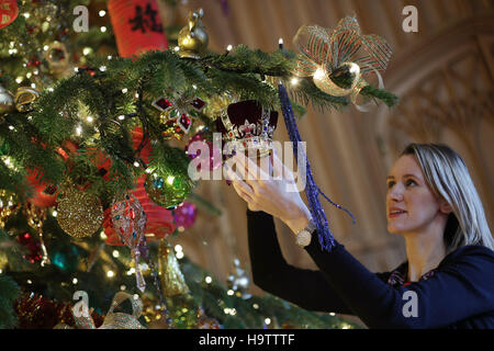 Royal Collection Trust Bedienstete verleiht den letzten Schliff ein 20ft Nordmann-Tanne in St Georges Hall, als Teil der Weihnachtsschmuck in Windsor Castle, Berkshire aufgestellt wird. Stockfoto