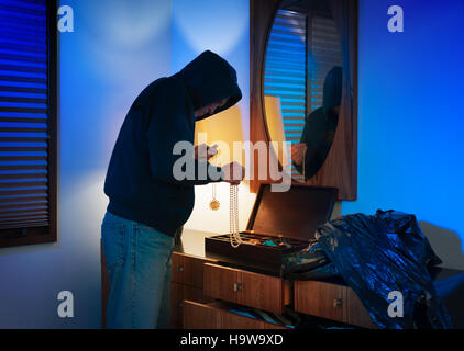Vermummte Einbrecher durchwühlen ein Schmuckkästchen in einem Heim Stockfoto
