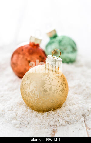 Bunte Weihnachtskugeln auf Schnee und weißen Hintergrund Stockfoto