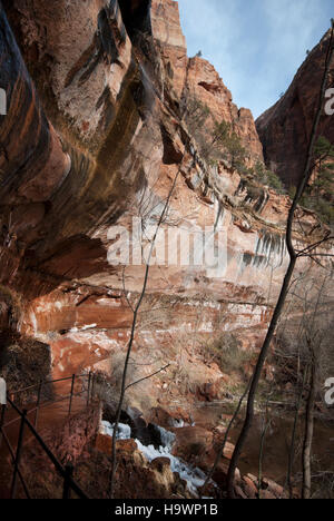 Der Winter verwandelt den Zion-Nationalpark mit schneebedeckten Felsen und dem ruhigen Lower Emerald Pool, der einen atemberaubenden Kontrast zu den kargen Ästen der Laubbäume bietet. Der Pool, ein beliebtes Wanderziel, ist im Winter ruhiger und bietet Besuchern eine ruhige Umgebung. Stockfoto