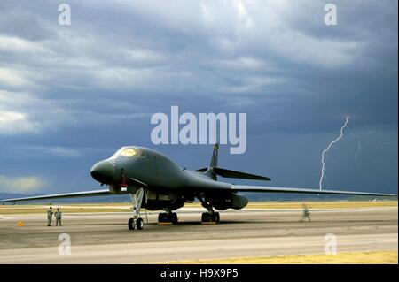 Blitzeinschläge in den stürmischen Himmel dahinter ein B-1 b Lancer strahlgetriebenen schwere strategische Bomber Flugzeug auf der Startbahn in Ellsworth Air Force Base in der Nähe von 9. September 2010 Box Elder, South Dakota. Stockfoto