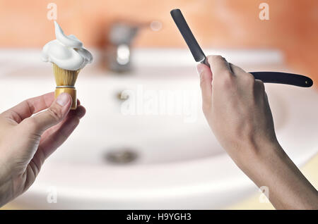 Rasiermesser und Bürste für Rasierschaum in der hand auf Hintergrund-Bad. Persönliche Betreuung. Werkzeuge für die Rasur. Stockfoto