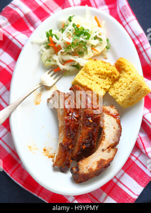 Draufsicht auf Knoblauch-Barbecue Sauce glasiert Baby Rücken Schweinerippchen mit Maisbrot und Krautsalat Stockfoto