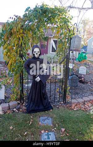 Halloween Sensenmann Skelett mit großen Beil Bewachung Friedhofstor im Vorgarten des Hauses. Fergus Falls Minnesota MN USA Stockfoto