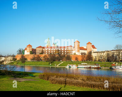 Krakau, Polen. Stadtbild mit Wawel-Hügel, Defnsive Wände, Turm der Kathedrale, Schloss, Weichsel, Schiffe, Hafen und parks im Herbst bei Sonnenuntergang. Stockfoto