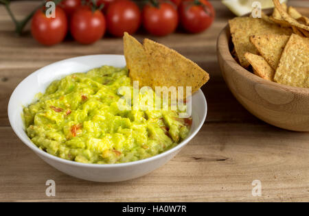 Guacamole in weiße Schüssel auf natürlichen hölzernen Schreibtisch. Stockfoto