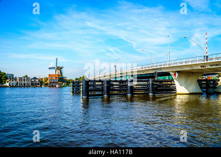 Moderne Zugbrücke über den Fluss Zaan an der historischen Stadt von Zaandijk in den Niederlanden mit einer Windmühle im Hintergrund Stockfoto