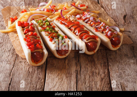 Hot Dogs mit Ketchup, Senf, Zwiebeln und Pommes frites Nahaufnahme auf dem Tisch. Horizontal, rustikal Stockfoto