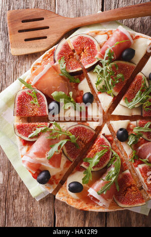 Pizza mit Feigen, Schinken, Kräutern, Oliven und Mozzarella Closeup auf dem Tisch. vertikale Ansicht von oben Stockfoto