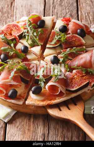 Leckere Pizza mit Feigen, Schinken, Rucola, Oliven und Käse-close-up auf dem Tisch. vertikale Stockfoto