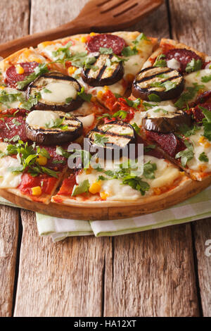 Pizza mit gegrillten Auberginen, Wurst, Mais und Käse Nahaufnahme auf dem Tisch. vertikale Stockfoto