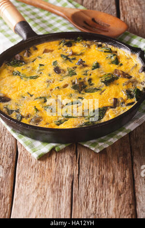 Italienische üppig mit Spinat, Cheddar-Käse und Pilzen in einer Pfanne Großaufnahme auf dem Tisch. vertikale Stockfoto