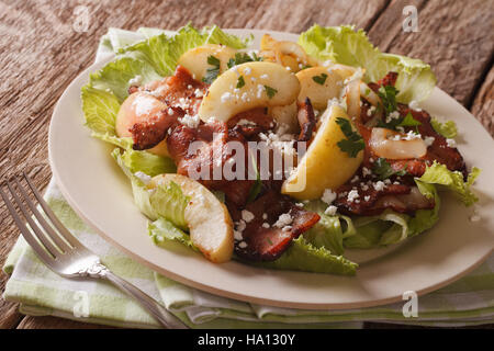 Köstlicher Salat mit gebratenem Speck, Zwiebel, gedünsteten Apfel und Ziege Käse Nahaufnahme auf einem Teller auf den Tisch. Horizontale Stockfoto