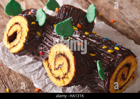 Traditionelle Weihnachten Yule Log Kuchen verziert mit Süßigkeiten Streusel auf dem Tisch. Horizontale Stockfoto