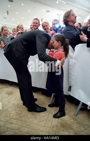 US-Präsident Barack Obama bückt sich, um eine persönliche Nachricht von einem jungen Mädchen zu hören, während die US-Botschaft-Meet &amp; greet im Hotel Adlon 16. November 2016 in Berlin, Deutschland. Stockfoto