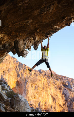 Männliche Bergsteiger hängen am Dach der Höhle beim Klettern Stockfoto