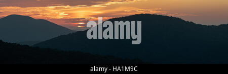 Ein atemberaubendes Panorama fängt die ruhige Schönheit eines Sonnenaufgangs über der Landschaft ein und zeigt das Licht am frühen Morgen und die umliegende Landschaft. Das Bild unterstreicht die Ruhe und natürliche Schönheit der Natur, perfekt für die Erkundung der täglichen Zyklen der Natur. Stockfoto