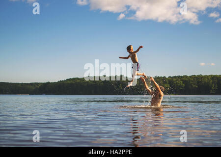 Vater Sohn in der Luft stehend in einem See zu werfen Stockfoto