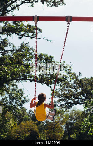 Mädchen sitzen auf einer Schaukel auf Spielplatz Stockfoto