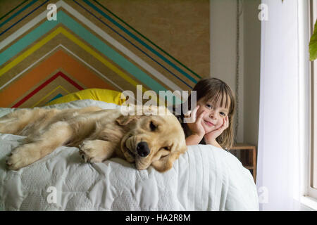 Mädchen und golden Retriever Hund auf Bett liegend Stockfoto