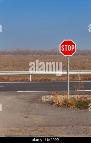 Stop-Schild am Scheideweg. Landstraße. Fahren Sie auf der Hauptstraße. Hauptstraße. Gefährlicher Weg. Verkehrszeichen zu stoppen. Stockfoto