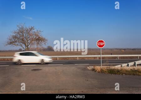 Stop-Schild am Scheideweg. Landstraße. Fahren Sie auf der Hauptstraße. Hauptstraße. Gefährlicher Weg. Verkehrszeichen zu stoppen. Stockfoto