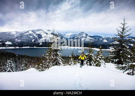 Eine ältere Frau, Schneeschuhwandern im Winter über dem See an einem stürmischen Tag Stockfoto