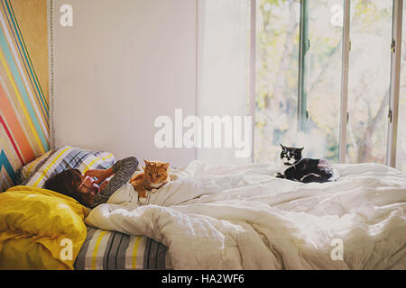 Mädchen im Bett mit zwei Katzen Stockfoto