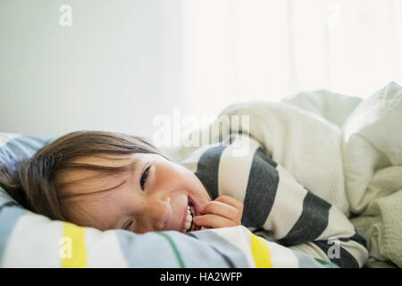 Porträt eines Mädchens liegend im Bett lachen Stockfoto