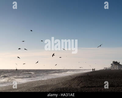 Der Strand windet Aldeburgh Suffolk im frühen Morgenlicht bei starkem mit Silhouette Menschen am Ufer und schwebenden Möwen Stockfoto
