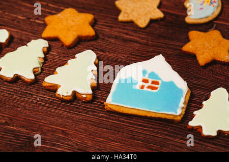 Lebkuchen, wie ein Haus und Tannen auf einem dunklen Hintergrund aus Holz geformt. Stockfoto