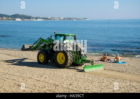 Zwei Touristen am Strand in der Nähe von Traktor Renourishment, Restaurierung, arbeitet Nachschub Sand in La Cala Mijas, Spanien. Stockfoto