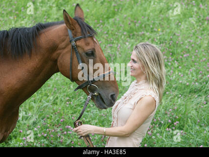 Junge, blonde Frau stand vor ihr Pferd Stockfoto