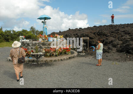 La Réunion, Frankreich - 29. Dezember 2002: Besucher, die die Statue der Patin mit Regenschirm in der Wallfahrtskirche der Lava Eruption auf La Reunio Stockfoto