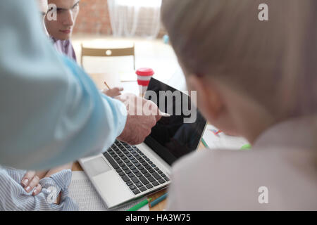 Junge Kollegen zusammen an ihrem Arbeitsplatz sitzen und auf Laptop-Bildschirm zeigen Stockfoto