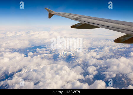 Der Blick aus einem Flugzeugfenster während des Fluges über die schneebedeckten Gipfel der französischen Alpen. Stockfoto