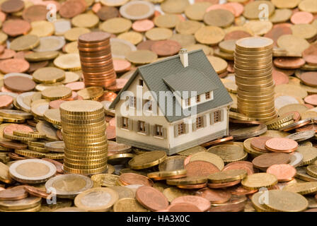 Miniaturhaus auf Münzen, symbolisches Bild für Haus und Finanzen Stockfoto