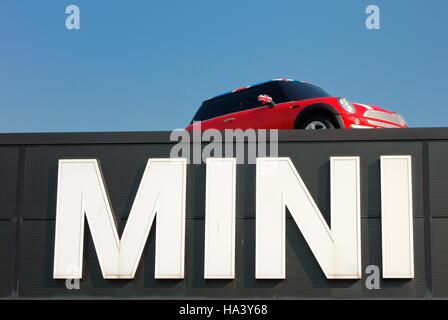 Mini-Auto auf dem Dach über riesige Mini-Schild Stockfoto