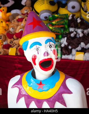 Ein bunte Arcade-Clown mit Preisen gestapelt hinter ihm. Stockfoto