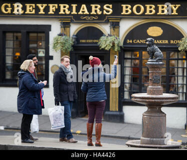 Touristen fotografieren Greyfriars Bobby-Statue, die vor Greyfrairs Kirk auf George iv Street Bridge in Edinburgh sitzt. Stockfoto