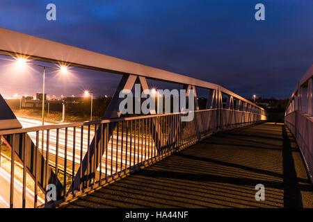 Schöner Sonnenuntergang Perspektive, Langzeitbelichtung Schuss eine Fußgängerbrücke über die stark frequentierten Autobahn M62 in Leeds Stockfoto