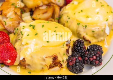 Einmal Krabbengebäck Eiern Benedict mit Beeren und deutschen Kartoffeln serviert Stockfoto