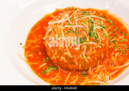 Eine sehr große italienische Fleischbällchen gebadet im Reich Pomodoro Sauce, garniert mit Parmesan und Petersilie Stockfoto