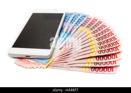 Smartphone über den Haufen von indonesische Rupiah (IDR) Banknoten auf dem weißen Hintergrund. Stockfoto