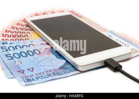 Smartphone über den Haufen von indonesische Rupiah (IDR) Banknoten auf dem weißen Hintergrund. Stockfoto