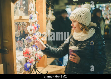 Junge hübsche Frau, die Auswahl der Geschenke am Weihnachtsmarkt. Winter-Urlaub-Souvenir-shop Stockfoto