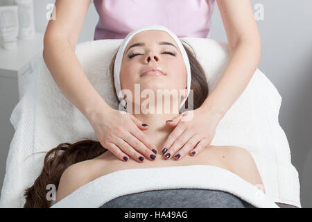 Schöne junge Frau empfangen Gesichtsmassage mit geschlossenen Augen in einem Spa-salon Stockfoto