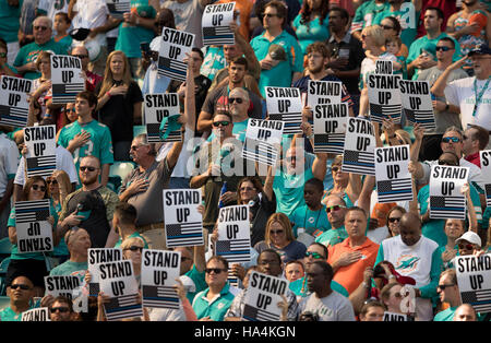 Miami Gardens, Florida, USA. 27. November 2016. Fans halten Stand Up Schilder für San Francisco 49ers Quarterback Colin Kaepernick (7), als er während der Nationalhymne im Hard Rock Stadium in Miami Gardens, Florida am 27. November 2016 kniet. Bildnachweis: Allen Eyestone/The Palm Beach Post/ZUMA Draht/Alamy Live-Nachrichten Stockfoto