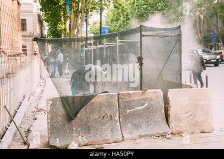 Tiflis, Georgien - 20. Mai 2016: Die Arbeiter, die Reparatur der Gehweg Pflaster hinter das Gehäuse an der Rustaveli Avenue im Frühling Sommer. Stockfoto