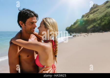 Schuss von zärtlich junges Paar am Strand. Mann und Frau umarmt im Freien an einem Sommertag. Flitterwochen am tropischen Strand zu genießen. Stockfoto